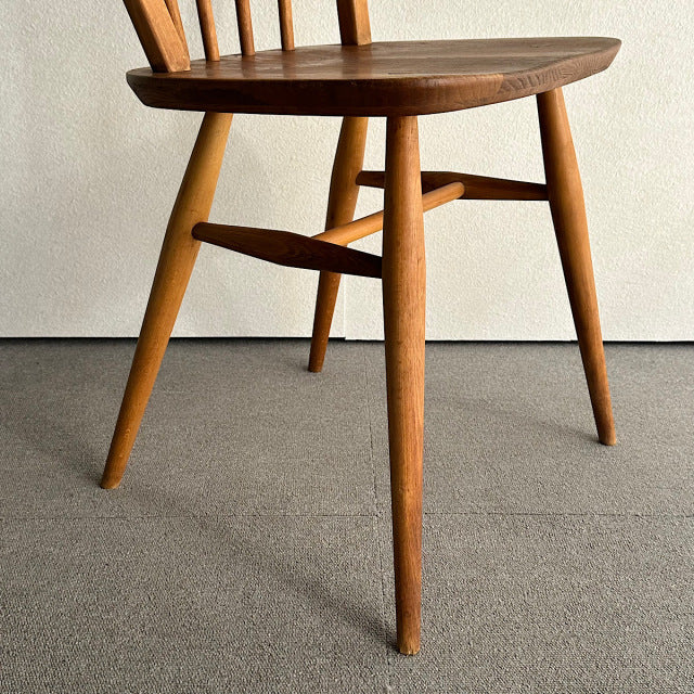 Vintage teak Ercol mid-century British hoop-back dining chair with slender tapered legs and visible wood grain.