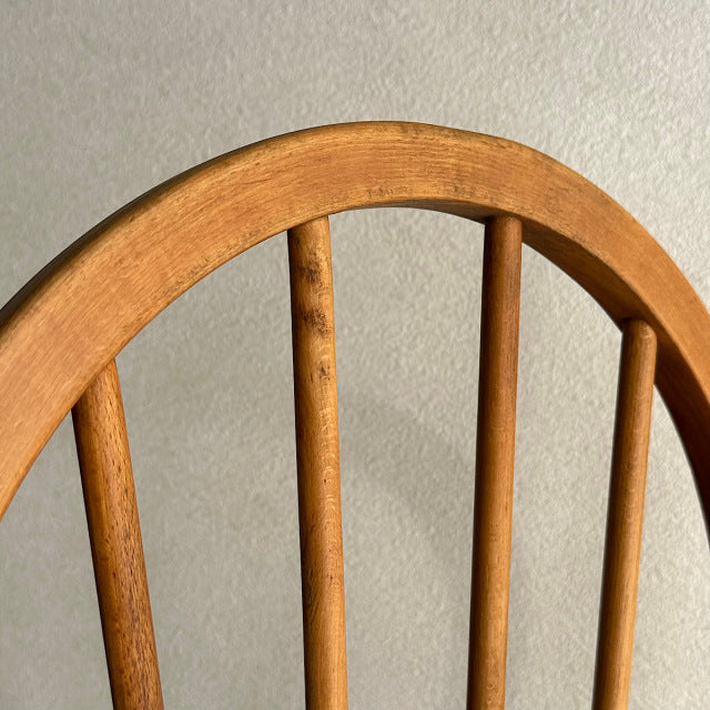 Vintage British mid-century Ercol hoop back chair in warm teak with visible wood grain and four slender vertical spindles.