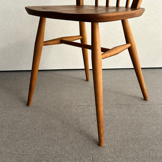 Mid-century British vintage Ercol hoop back chair in warm teak with smooth wood grain and tapered legs.