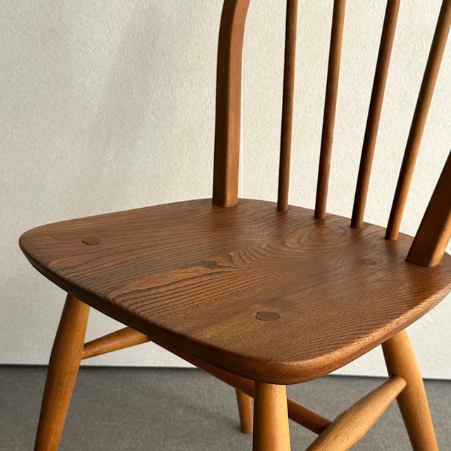 Vintage British mid-century Ercol hoop back chair in polished teak with visible wood grain and slender spindled back.