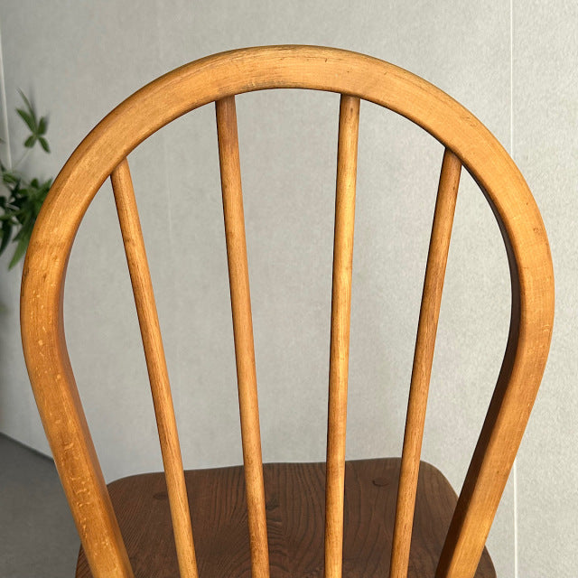 Vintage teak Ercol mid-century British hoop-back dining chair with four vertical spindles and smooth curved top rail.