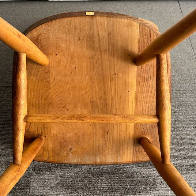 Vintage British mid-century Ercol hoop back chair in teak with visible wood grain and turned legs viewed from below.