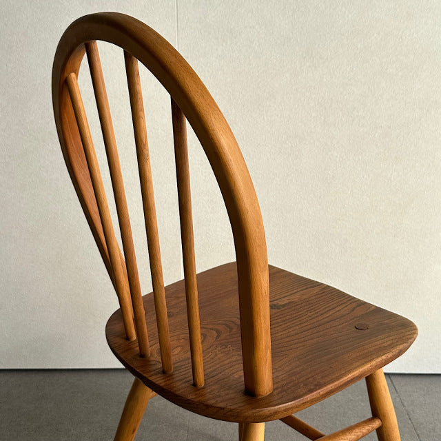 Vintage British mid-century Ercol hoop-back dining chair in warm teak with slender vertical spindles and gently curved.