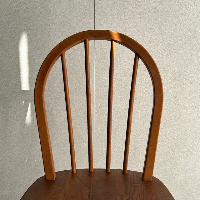 Vintage British mid-century teak Ercol hoop back dining chair with curved spindles and visible wood grain.