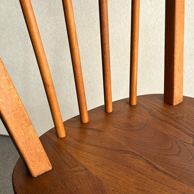 Mid-century British vintage ERCOL hoop back chair in warm teak with smooth wood grain and slender spindled backrest.
