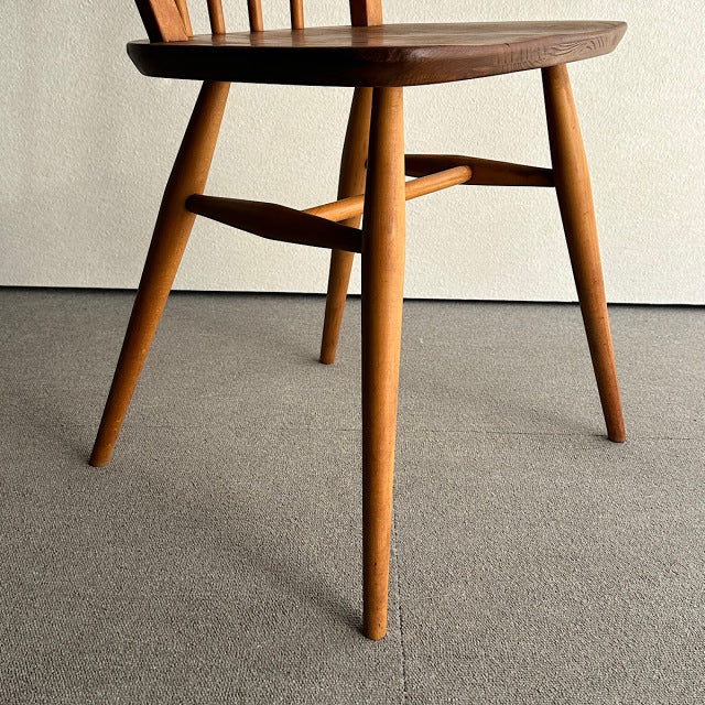 Mid-century British vintage Ercol hoop back chair in warm teak with visible wood grain and tapered legs.