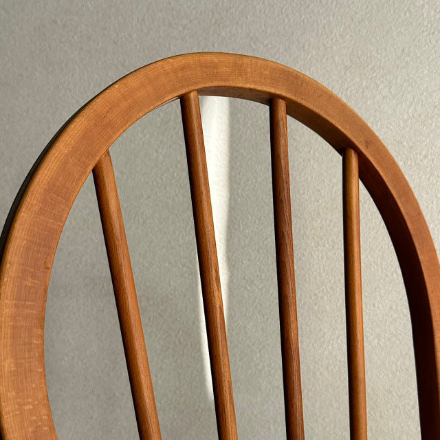 Vintage British mid-century Ercol hoop back chair in warm teak wood with smooth curved wood grain and four vertical spindles.