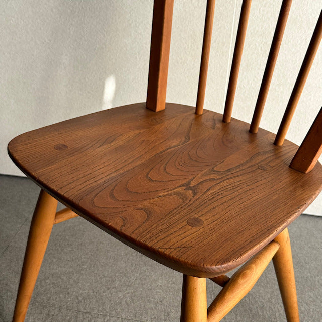 Mid-century British vintage Ercol hoop back chair in rich teak with visible wood grain and slender spindle legs.