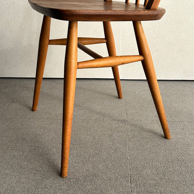 Mid-century British vintage Ercol hoop back chair in teak with smooth rounded legs and visible wood grain.