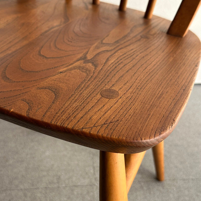 Close-up of vintage British mid-century teak chair seat showing rich wood grain and smooth rounded edges with tapered legs.