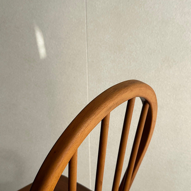 Mid-century British vintage Ercol hoop back chair in warm teak with smooth curved top rail and slender vertical spindles.