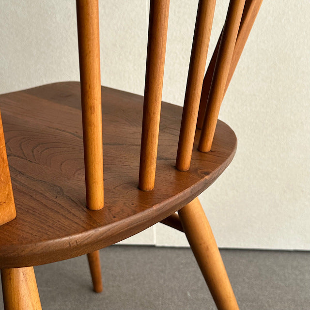 Vintage British mid-century Ercol hoop back chair in warm teak, showcasing smooth wood grain, slender spindled backrest, and .