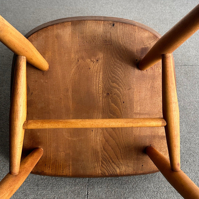 Vintage mid-century British Ercol hoop back chair in warm teak, showcasing smooth wood grain and rounded legs from Denmark.