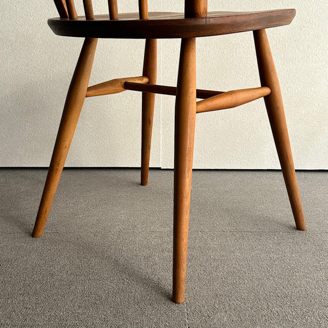 Vintage British mid-century Ercol hoop back chair in warm teak with tapered legs and smooth wood grain.