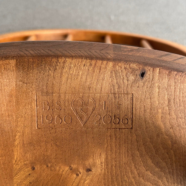 Close-up of teak wood grain and British mid-century Ercol chair stamp dated 1956 with smooth curved backrest and natural.