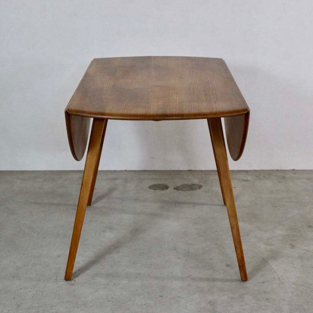 Vintage British Ercol mid-century teak dining table with drop-leaf design and tapered legs.