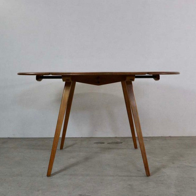 Mid-century British vintage Ercol dining table in teak with drop-leaf top and angled tapered legs showing rich wood grain.