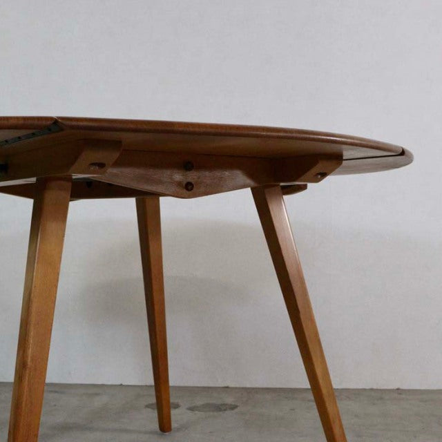 Mid-century British vintage ERCOL teak dining table with drop-leaf, angled legs, and smooth wood grain.