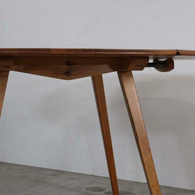 Mid-century British Ercol dining table in teak with drop-leaf design, tapered legs, and smooth wood grain.