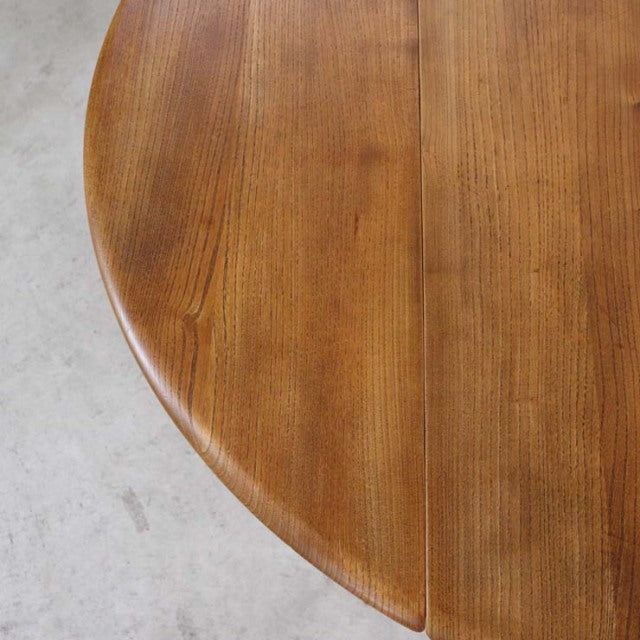 Mid-century British vintage Ercol dining table in teak with round drop-leaf design and visible wood grain.