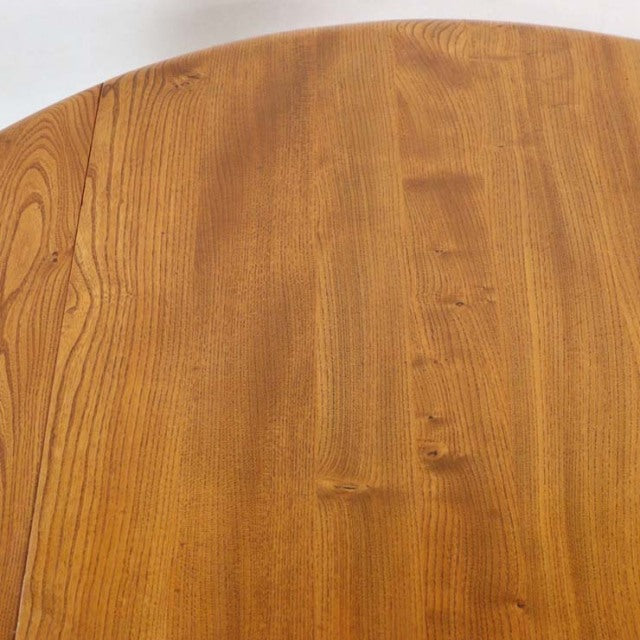 Vintage British mid-century Ercol teak dining table with oval drop-leaf top showcasing rich wood grain and smooth finish.
