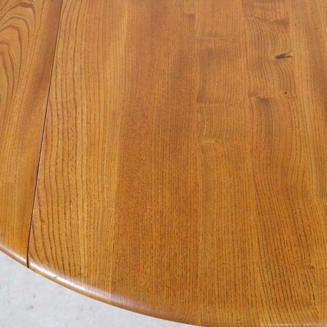 Close-up of vintage British mid-century Ercol dining table drop-leaf in warm teak with visible wood grain and smooth rounded .