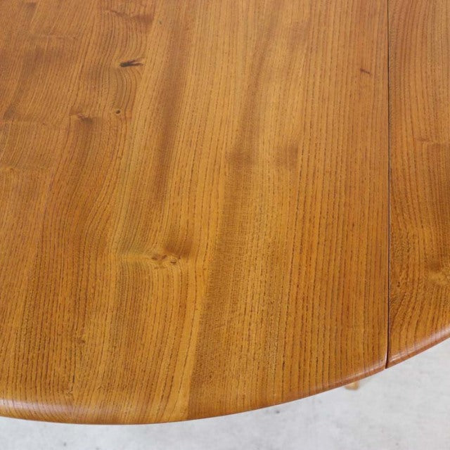 Vintage British mid-century teak dining table with smooth grain and rounded drop-leaf edge.