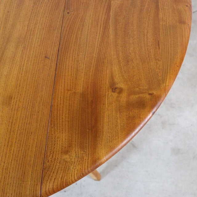Vintage British mid-century teak dining table with rich wood grain and rounded edge, showing drop-leaf design.