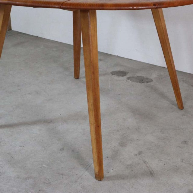 Mid-century British vintage Ercol dining table in warm teak with tapered legs and round drop-leaf top showing rich wood grain.