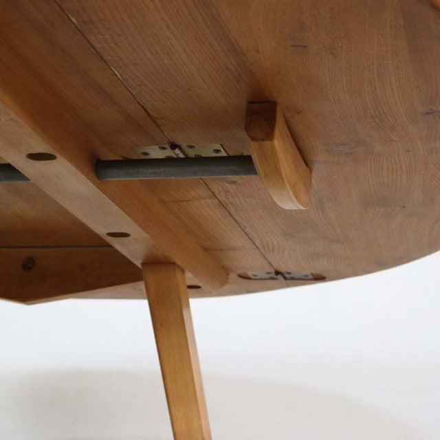 Close-up of vintage British mid-century Ercol teak dining table leg and drop-leaf mechanism showing smooth wood grain and.
