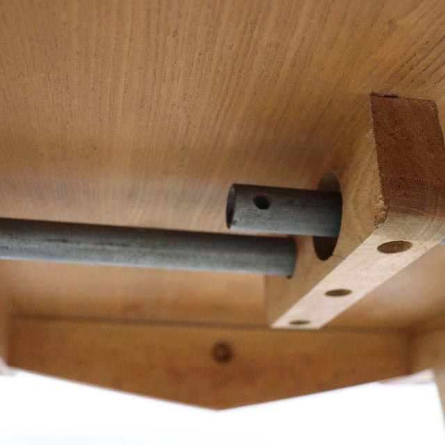 Close-up of vintage British mid-century Ercol teak dining table drop-leaf mechanism showing smooth wood grain and sturdy.