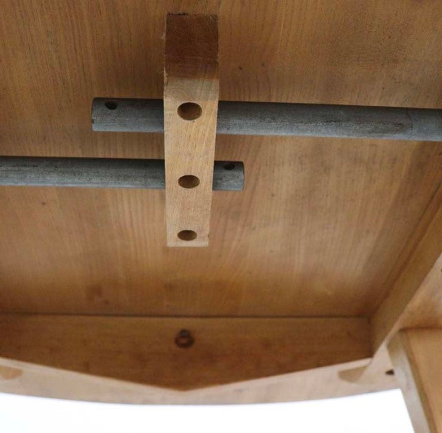 Underside of vintage teak Ercol mid-century British drop-leaf dining table showing wood grain and brass support bars.