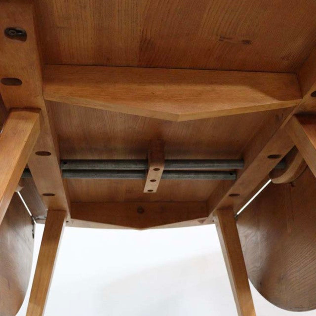 Underside view of vintage British mid-century Ercol teak dining table showing drop-leaf mechanism and solid wood legs with.
