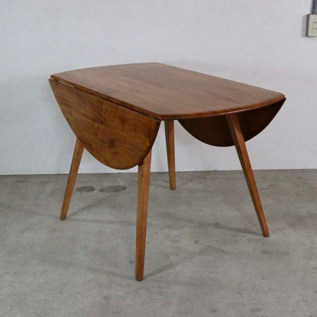 Mid-century British vintage Ercol teak dining table with rounded drop-leaf top and angled legs.