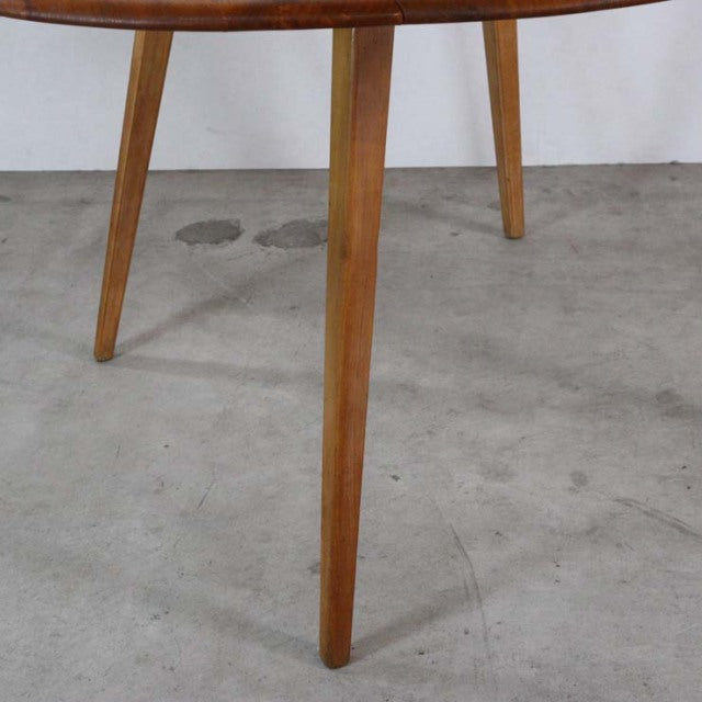 Mid-century British vintage Ercol dining table with teak wood grain and tapered legs on concrete floor.