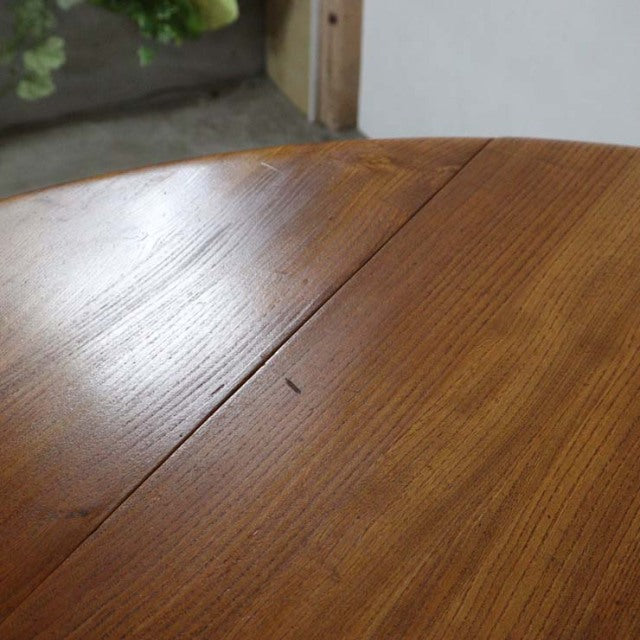 Close-up of vintage British mid-century Ercol dining table in warm teak with visible wood grain and a drop-leaf edge detail.