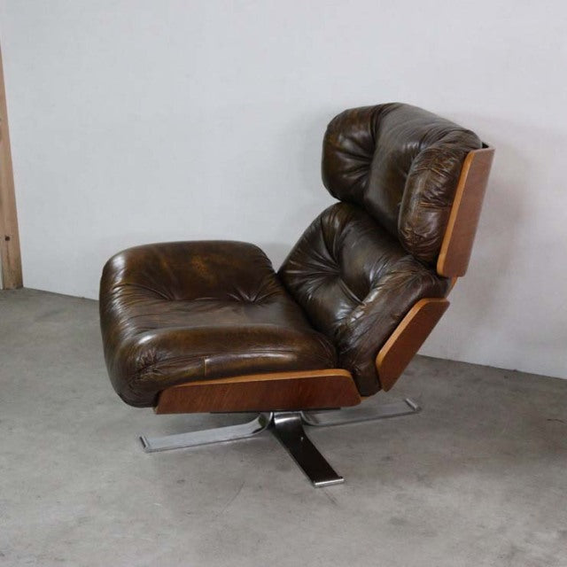 Vintage mid-century British leather lounge chair with rich teak wood frame and chrome swivel base, featuring tufted cushions .
