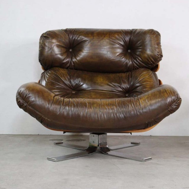Vintage mid-century British leather lounge chair with deep button tufting, curved armrests, and polished teak swivel base.