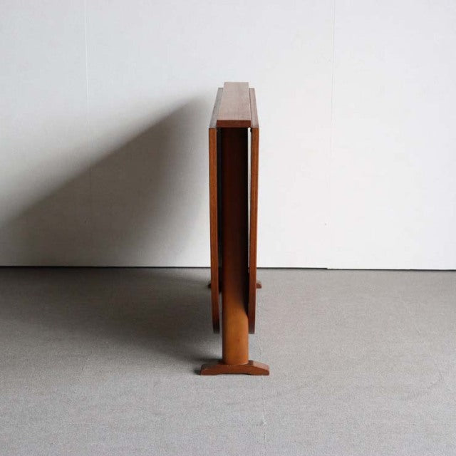 Folded vintage teak dining table with slender tapered legs, mid-century British-Danish design.