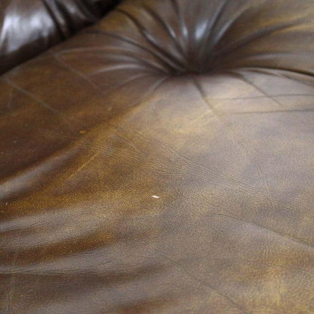 Close-up of vintage mid-century British leather sofa seat with rich patina and fine natural creases on brown leather.