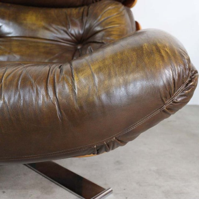 Mid-century vintage British leather armchair with rich teak wood grain and tufted cushion detailing.