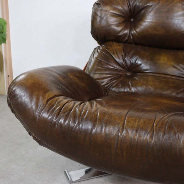 Mid-century British vintage leather armchair with rich brown tufted upholstery and sleek teak legs.