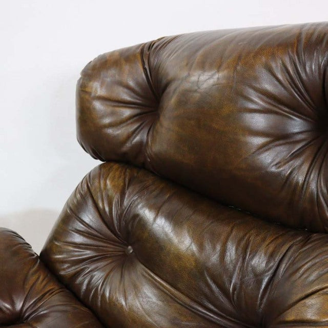 Vintage mid-century British leather sofa with deep button tufting and rich brown patina on curved cushions.