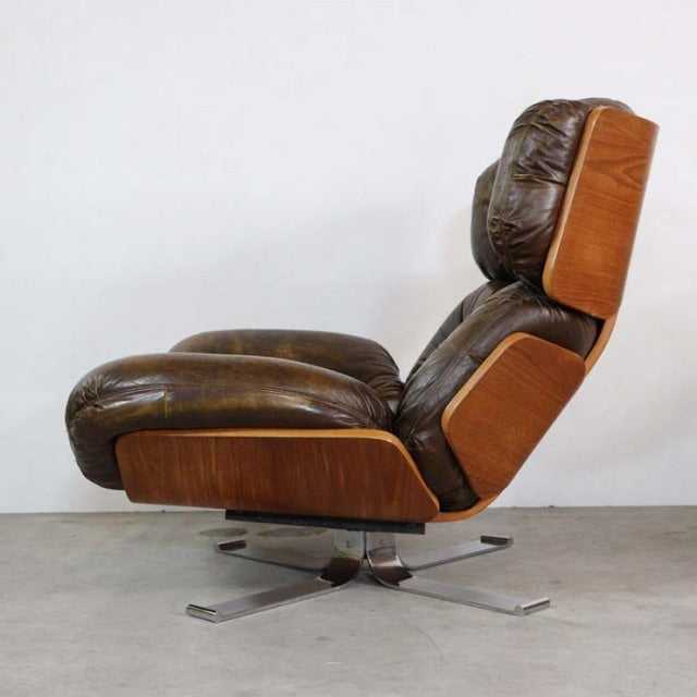 Vintage mid-century leather armchair with teak wood frame, British-Denmark design, and metal swivel base.