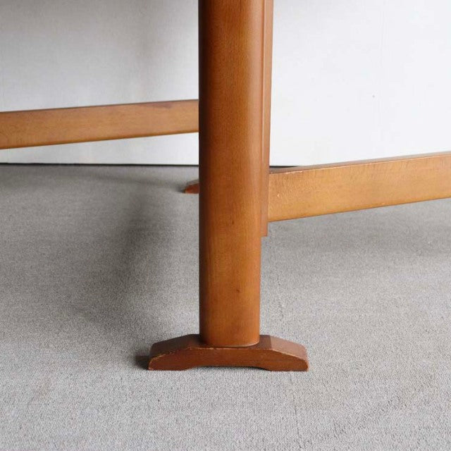 Close-up of mid-century vintage teak dining table leg with round column and sturdy square base, showcasing smooth wood grain .