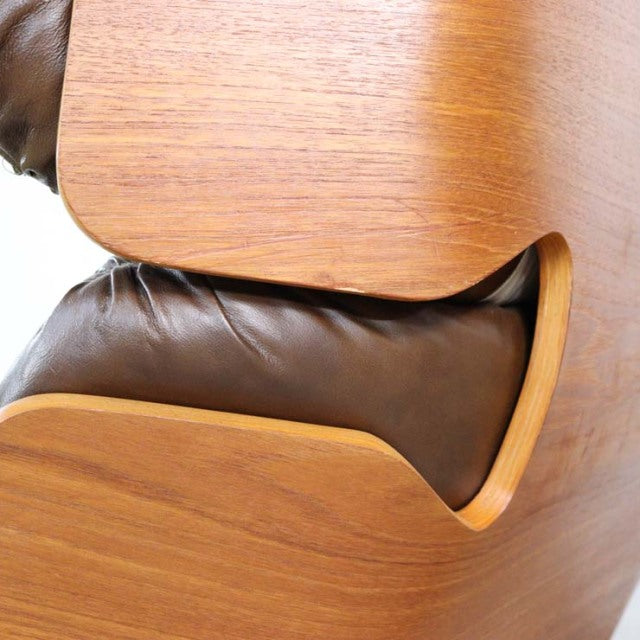 Close-up of vintage mid-century British leather armchair with smooth teak wood frame featuring visible grain and curved edges.