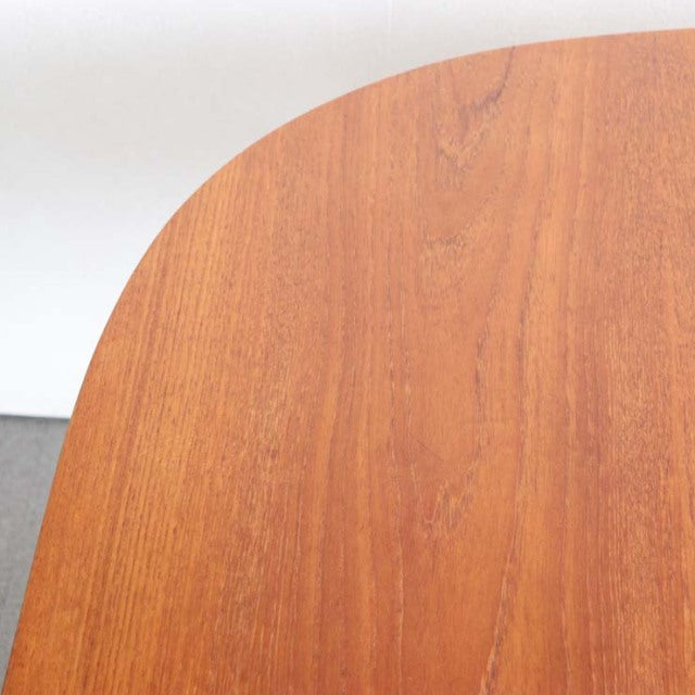 Vintage mid-century British teak dining table with smooth rounded corner and visible wood grain.