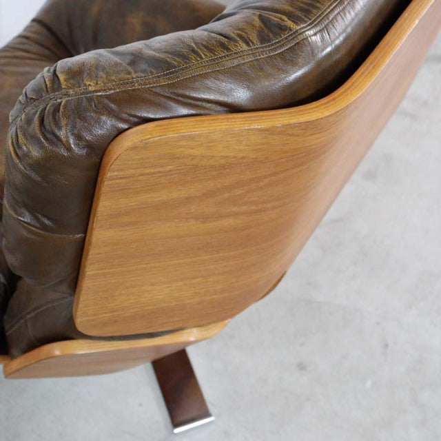 Mid-century vintage British leather armchair with rich teak wood frame and curved armrests showing natural grain.