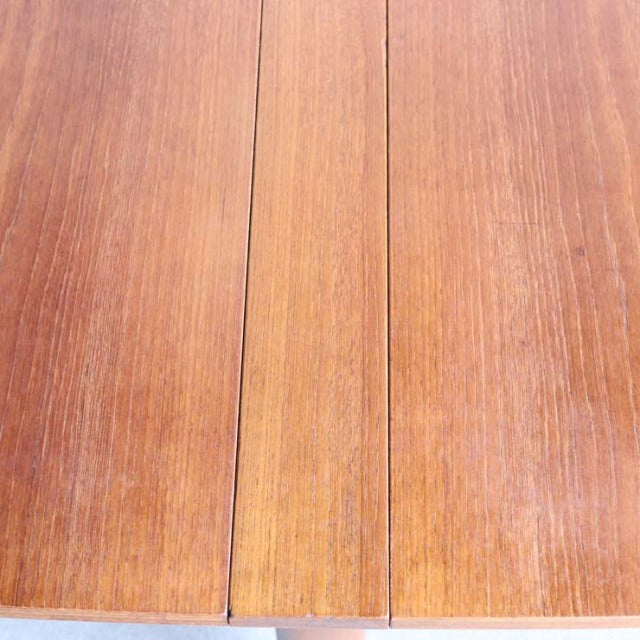 Mid-century British vintage teak dining table with smooth wood grain and folding design.