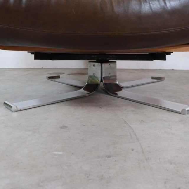 Mid-century British vintage leather chair base with polished chrome star legs on concrete floor.